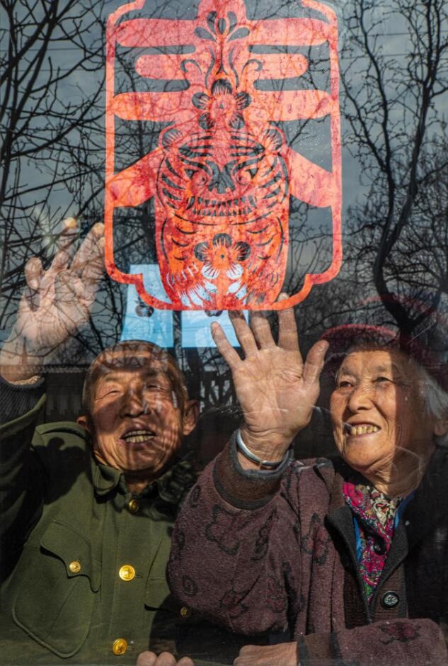 臘月里，霍州市師莊鄉(xiāng)馮南垣村村民師榮光(左)在災(zāi)后重建的新家里貼窗花。(霍州市委宣傳部供圖)