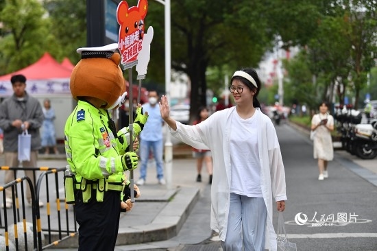 6月7日上午9時(shí)，隨著鈴聲的響起，2023年江西高考正式開(kāi)考，江西省的53.57萬(wàn)考生以縣（區(qū)）為單位隨機(jī)安排在全省256個(gè)考點(diǎn)、18968個(gè)考場(chǎng)參加高考。圖為“小熊交警”和考生擊掌鼓勵(lì)。 人民網(wǎng)記者 時(shí)雨攝