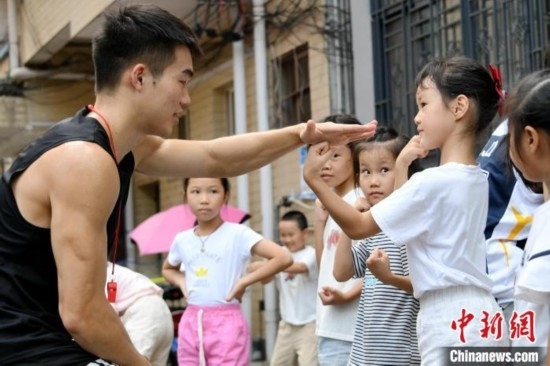 圖為大學(xué)生志愿者在組織孩子們參加體育健身活動。廖光福 攝