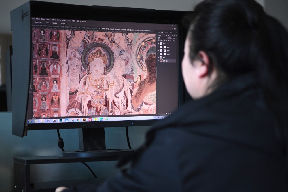 敦煌研究院文物數(shù)字化保護團隊圖像處理人員年海麗在拼接壁畫圖像（2023年4月25日攝）。數(shù)字化探索為莫高窟的保護與傳承開辟了全新路徑，數(shù)字技術(shù)讓敦煌文物走出洞窟，跨出國門，走向“永久保存、永續(xù)利用”。新華社記者 陳斌 攝