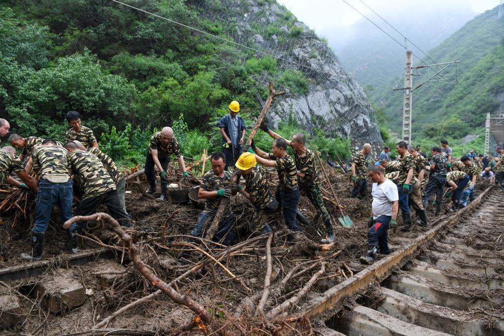 8月1日，在北京市門頭溝區(qū)水峪嘴村附近一段被阻斷的鐵路線上，中鐵六局工作人員在清理軌道上的雜物，全力恢復(fù)交通。新華社記者 鞠煥宗 攝