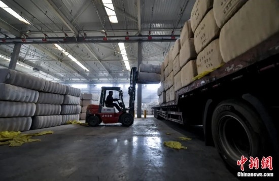 新疆喀什綜合保稅區(qū)，喀什啟路國際貿易有限公司的倉庫內，工人正在裝載從塔吉克斯坦和烏茲別克斯坦進口的棉花。劉新攝