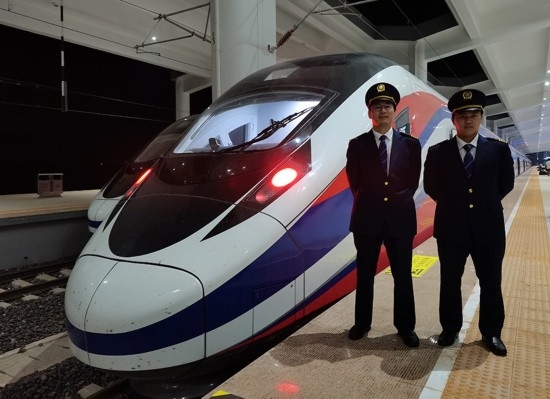 劉銀能（右一）與中國師父鄔俊鴻在動車組前合影。受訪者供圖