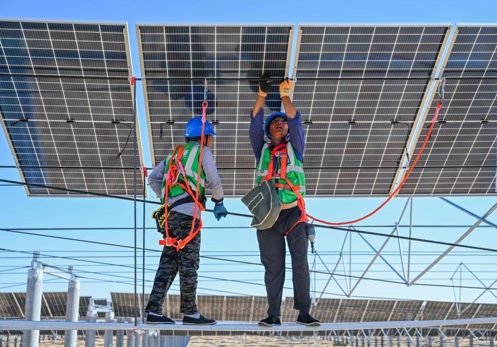 2023年7月22日，工人在位于內(nèi)蒙古杭錦旗庫(kù)布其沙漠億利生態(tài)示范區(qū)的蒙西基地庫(kù)布其200萬(wàn)千瓦光伏治沙項(xiàng)目工地安裝光伏板。新華社記者 劉磊 攝