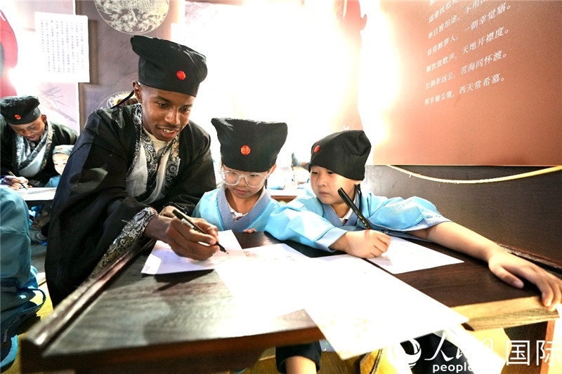 圖為選手與同學們一起寫書法。人民網 盧鵬宇攝