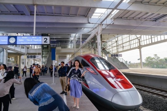  10月17日，在印度尼西亞萬隆德卡魯爾站，乘客在站臺(tái)上和雅萬高鐵高速動(dòng)車組列車合影。新華社記者 徐欽 攝