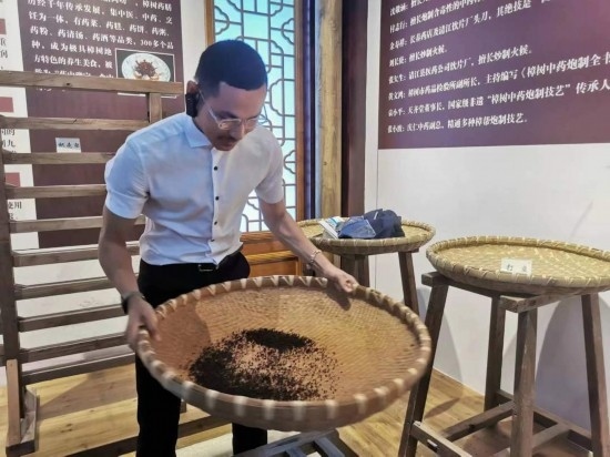 2023“一帶一路”媒體合作論壇聯(lián)合采訪團團員在非遺文化展示館體驗中藥炮制技藝。（本報記者 黃超攝）