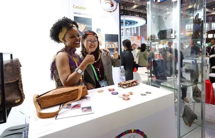 11月6日，一位參觀者（右）在第六屆進(jìn)博會(huì)國(guó)家展南非展臺(tái)試戴傳統(tǒng)首飾。