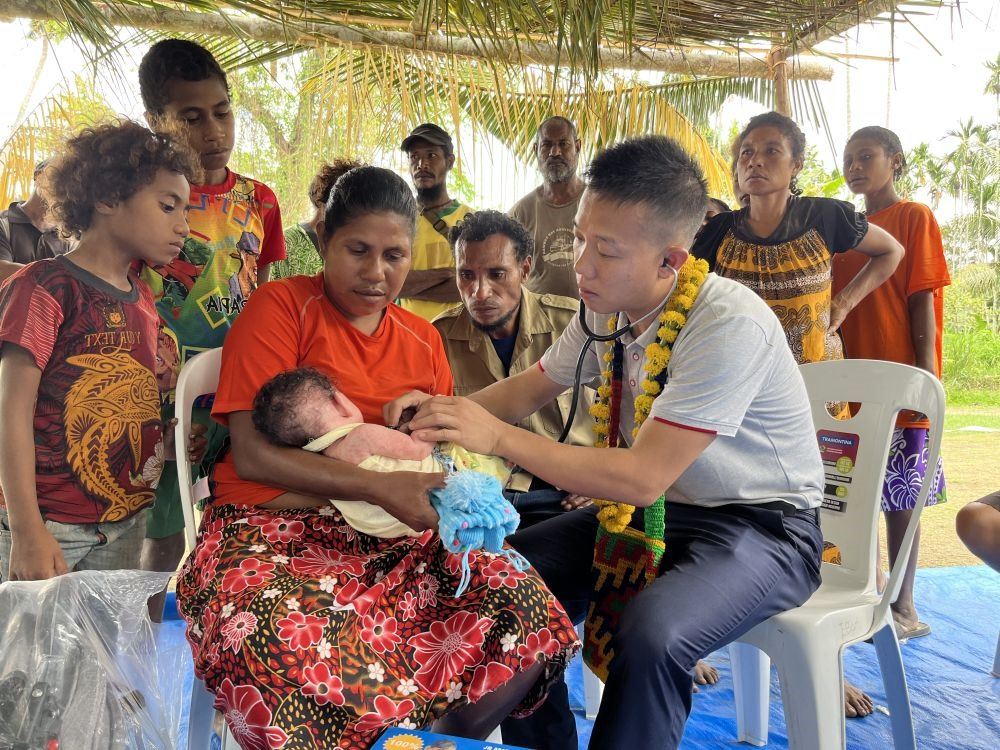 2023年8月5日，在巴布亞新幾內(nèi)亞中央省的一個村莊里，第12批援巴新中國醫(yī)療隊副隊長、新生兒科副主任醫(yī)師劉振球為嬰兒泰樂聽診檢查。泰樂出生時患有重癥，一度生命垂危，經(jīng)過劉振球與當(dāng)?shù)蒯t(yī)護(hù)人員的救治最終痊愈。從2002年起，中國連續(xù)向巴新派出12批醫(yī)療隊，為提高巴新醫(yī)療衛(wèi)生水平作出積極貢獻(xiàn)。