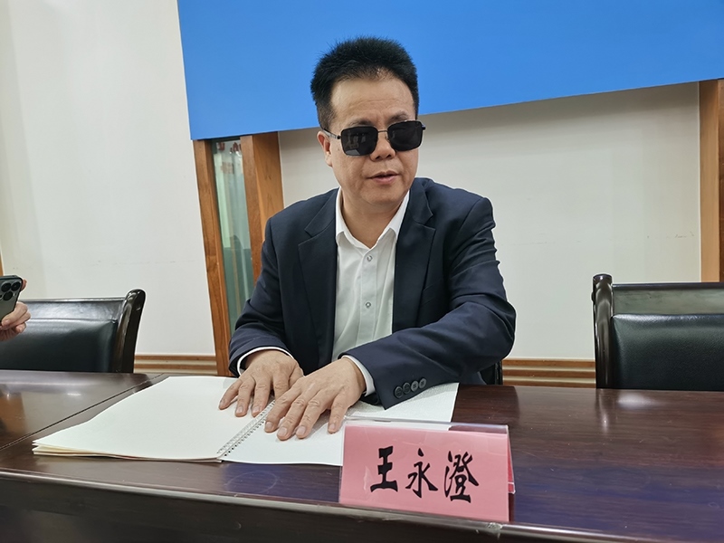 全國(guó)人大代表王永澄正在閱讀盲文版代表建議答復(fù)。本報(bào)記者 張 璁?dāng)z