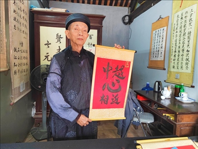 越南首都河內(nèi)文廟內(nèi)，阮明珠展示“中越心相近”書(shū)法作品。