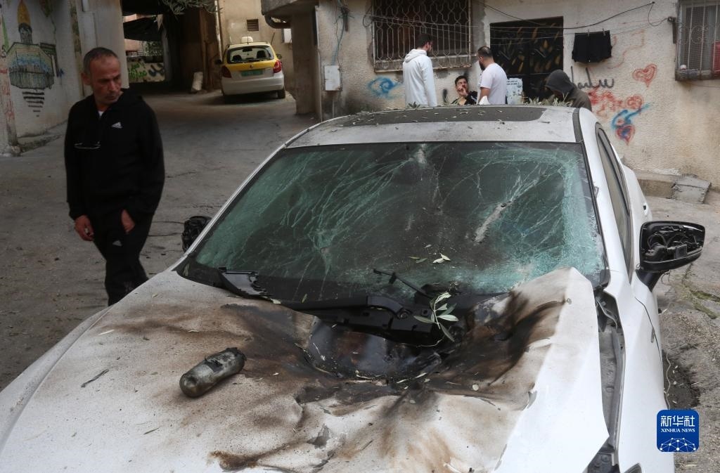 12月17日，在約旦河西岸城市圖勒凱爾姆附近的一處難民營，人們查看在沖突中損毀的車輛。新華社發(fā)（尼達(dá)爾·艾仕塔耶?dāng)z）
