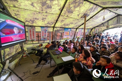 12月22日，在積石山縣大河家鎮(zhèn)大河村安置點，陸軍76集團軍某旅搭建的“臨時學(xué)?！眱?nèi)，小朋友正在看動畫片。人民網(wǎng)記者 翁奇羽攝