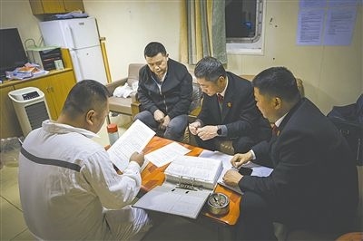圖②：法官向船長講解相關(guān)法律規(guī)定，查看船舶資料，并與船方辦理扣押船舶的手續(xù)。