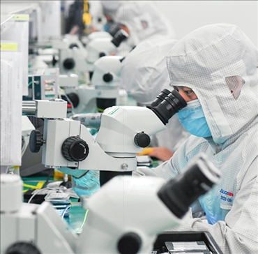 在位于武漢中國(guó)光谷的光電器件研發(fā)制造商——武漢光迅科技股份有限公司生產(chǎn)車(chē)間內(nèi)，技術(shù)人員在光模塊生產(chǎn)線作業(yè)（2023年4月11日攝）。程敏攝/本刊