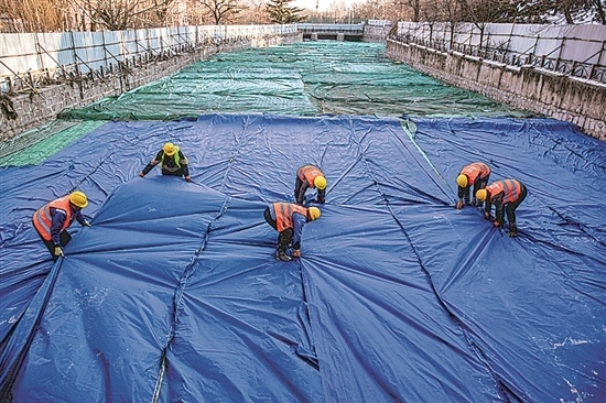 1月3日，房山區(qū)東風(fēng)街道，工人正在修復(fù)的河道內(nèi)給混凝土鋪設(shè)保溫布。