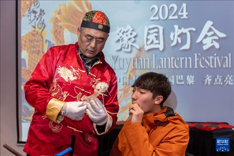 1月28日，在上海豫園舉行的民俗活動(dòng)上，美國馬斯卡廷中學(xué)學(xué)生在非遺傳承人的指導(dǎo)下吹糖偶。 新華社記者 王翔 攝