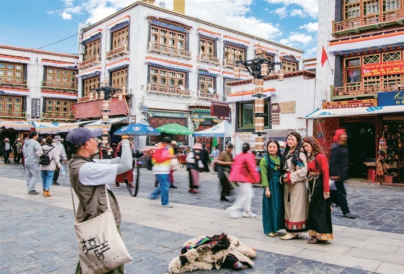 千年八廓街，見證民族團(tuán)結(jié)。2021年7月，習(xí)近平總書記來到位于西藏拉薩老城區(qū)的八廓街，感慨地說：“千年八廓街，是我們各民族建起來的八廓街。各民族文化在這里交流交往交融，我們中華民族的大家庭在這里其樂融融?！眻D為2023年6月13日，游客身著藏裝在八廓街拍照留念。 新華社記者 姜帆/攝