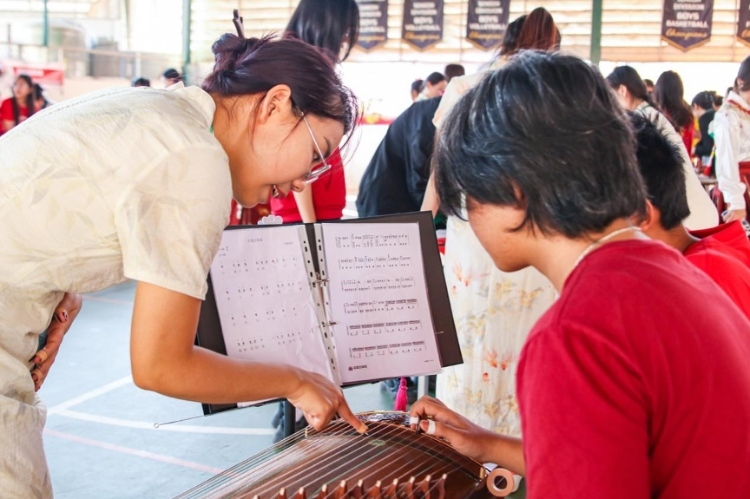 志愿者教師指導學生彈奏古箏。活動主辦方供圖