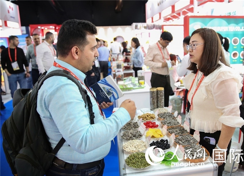 圖為一家中國干果參展企業(yè)代表與采購商洽談。人民網(wǎng) 塔里克·易卜拉欣攝