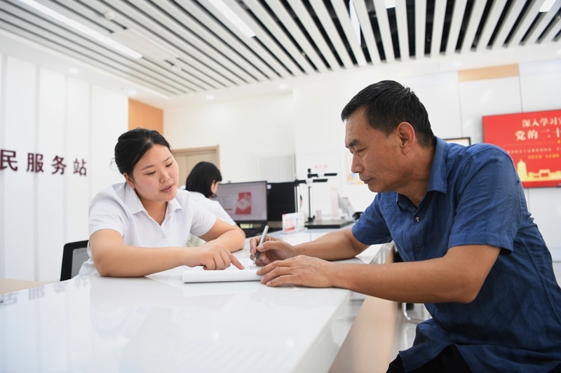 2023年5月23日，河北雄安新區(qū)容東片區(qū)南文營社區(qū)居民（右）在社區(qū)便民服務站辦理業(yè)務。