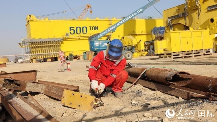 工人正在龍門吊吊裝現(xiàn)場切割金屬件。人民網(wǎng)記者管克江攝