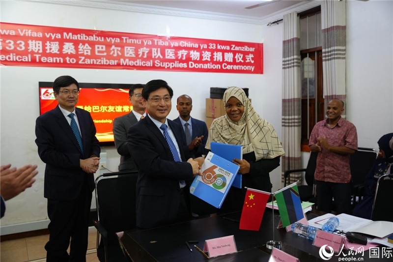 江蘇省蘇北人民醫(yī)院黨委書記束余聲與桑衛(wèi)生部首席秘書哈比巴交換捐贈書。中國援桑醫(yī)療隊供圖