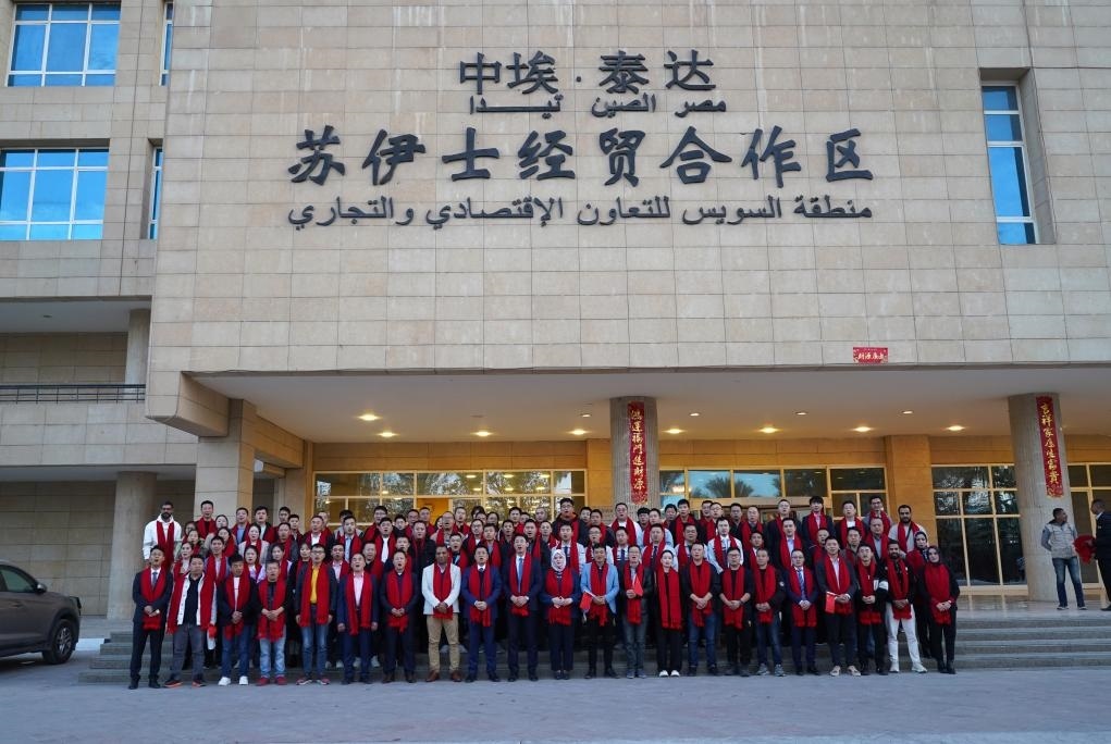 2024年2月11日，在位于埃及蘇伊士省的中埃·泰達(dá)蘇伊士經(jīng)貿(mào)合作區(qū)，中埃員工在合作區(qū)辦公大樓前合影拜年。新華社發(fā)（泰達(dá)合作區(qū)供圖）