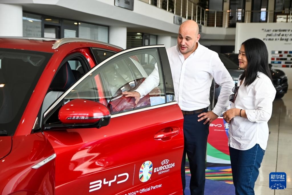 2024年5月29日，在馬耳他比爾基卡拉，馬耳他哈桑-扎米特汽車公司首席執(zhí)行官德古阿拉（左）介紹一輛比亞迪純電動汽車。新華社發(fā)（喬納森·博格 攝）
