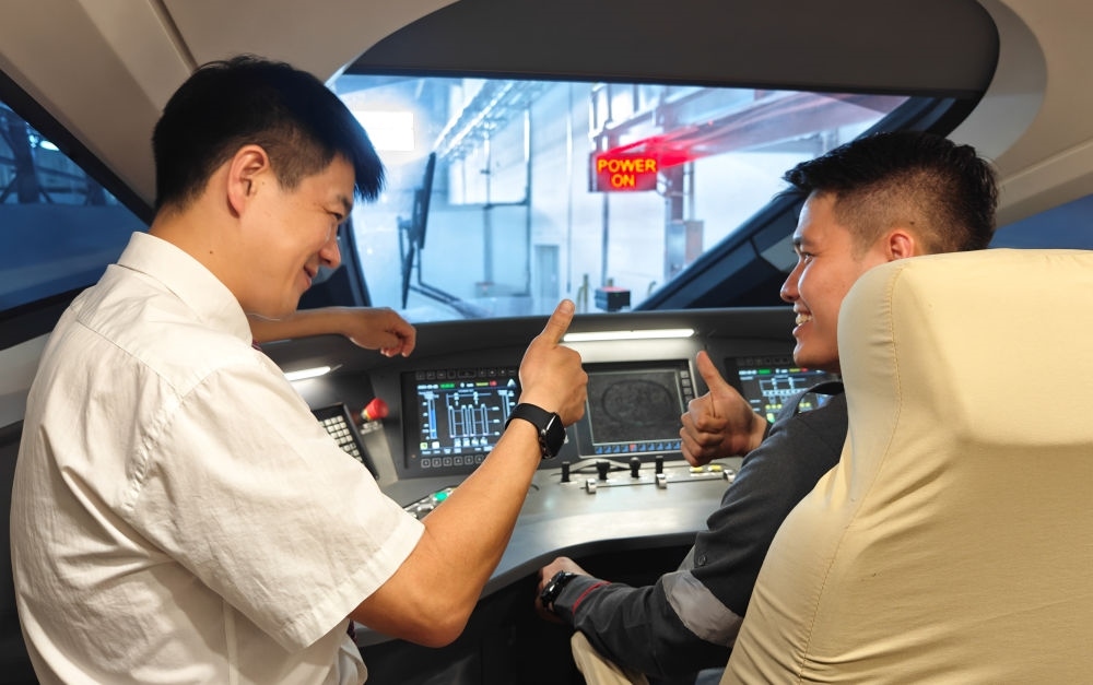 2023年8月25日，在印度尼西亞萬隆的雅萬高鐵德卡魯爾動(dòng)車所內(nèi)，中國(guó)師傅穆振（左）向印尼火車司機(jī)塞蒂亞萬講解動(dòng)車組出庫(kù)前的上電作業(yè)。新華社記者 徐欽 攝