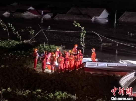  7月6日凌晨3時，在湖南岳陽華容縣團洲垸洞庭湖一線堤防，救援人員剛剛完成一次救援任務(wù)，遠處是被淹的民房。中新社記者 白祖偕 攝