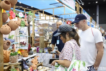 游客在蘭納博覽會特色展位上選購工藝品。人民網(wǎng)記者楊一攝