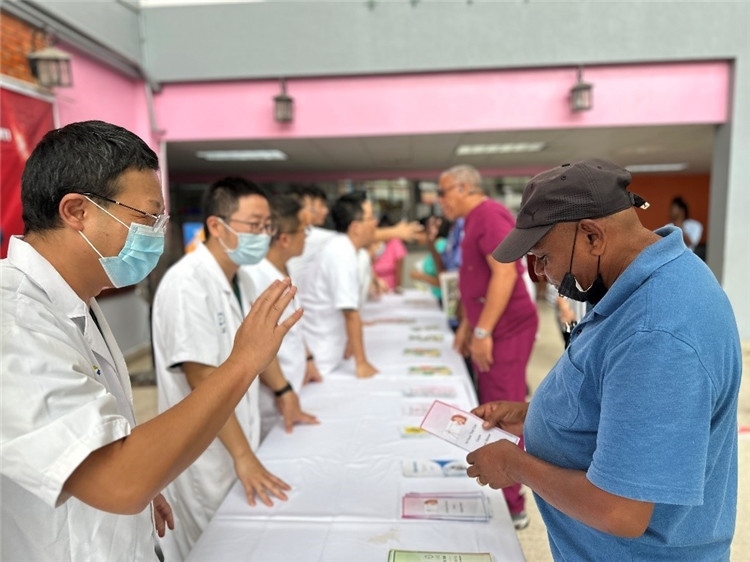 援圭醫(yī)療隊隊員們在啟動儀式上為當(dāng)?shù)孛癖姺职l(fā)宣傳手冊。中國援助圭亞那醫(yī)療隊供圖