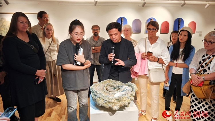 參展人、景德鎮(zhèn)陶瓷大學(xué)設(shè)計(jì)藝術(shù)學(xué)院副院長余劍峰（中）向來賓介紹參展作品。人民網(wǎng)記者 殷淼攝