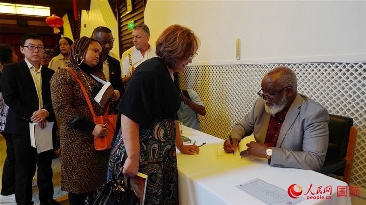 譚哲理在活動現(xiàn)場簽名贈書。人民網(wǎng) 劉暢攝