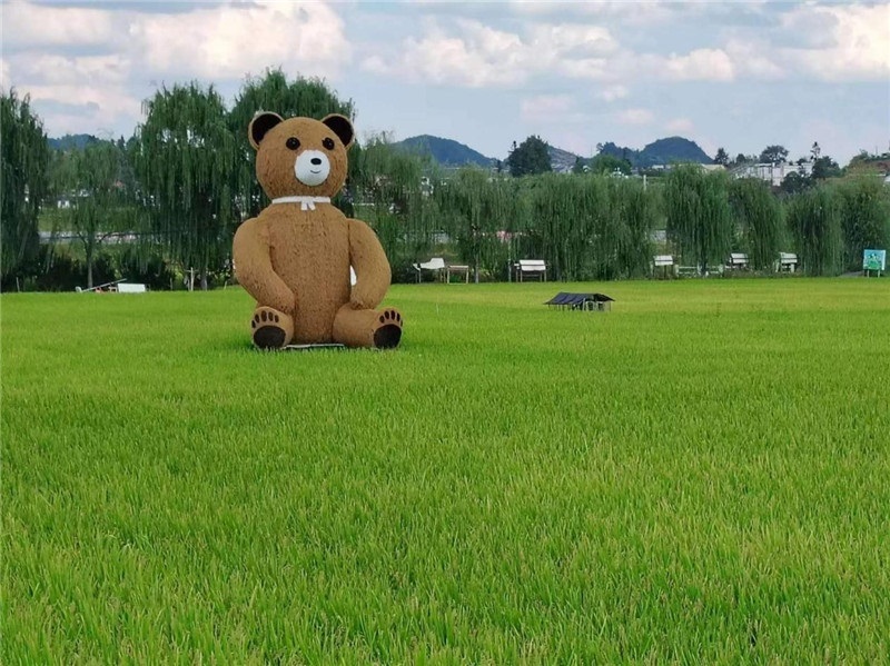 稻穗搖曳，垂柳依依，山嵐多姿，好一幅歲月靜好山鄉(xiāng)恬靜圖。這憨厚俏皮的熊玩偶造型，像是亂入其中，形成現(xiàn)代與傳統(tǒng)、好動與寧靜的反差感，讓人過目不忘，也讓人莞爾一笑。（哈薩克斯坦鳳凰24新聞社總編輯兼首席執(zhí)行官克馬爾·馬山羅攝）