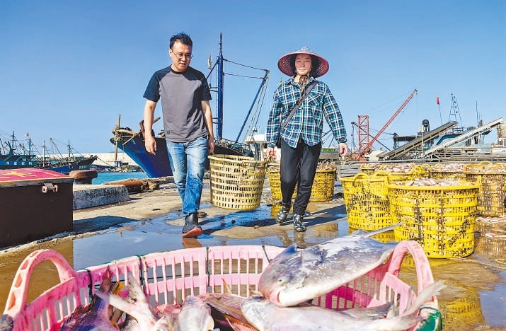 許小斌（左）和漁民一起搬運海鮮。本報記者 付 文攝