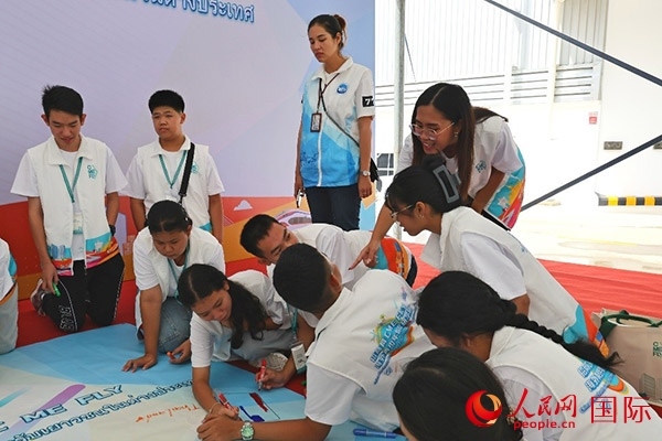 泰國學生在開營儀式展板上繪制圖案。人民網(wǎng)記者 白元琪攝