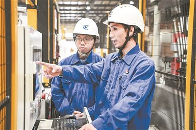在廣西柳工機(jī)械股份有限公司生產(chǎn)車間內(nèi)，一名高級技師（右）給徒弟講解數(shù)控設(shè)備操作細(xì)節(jié)。新華社記者 曹祎銘攝