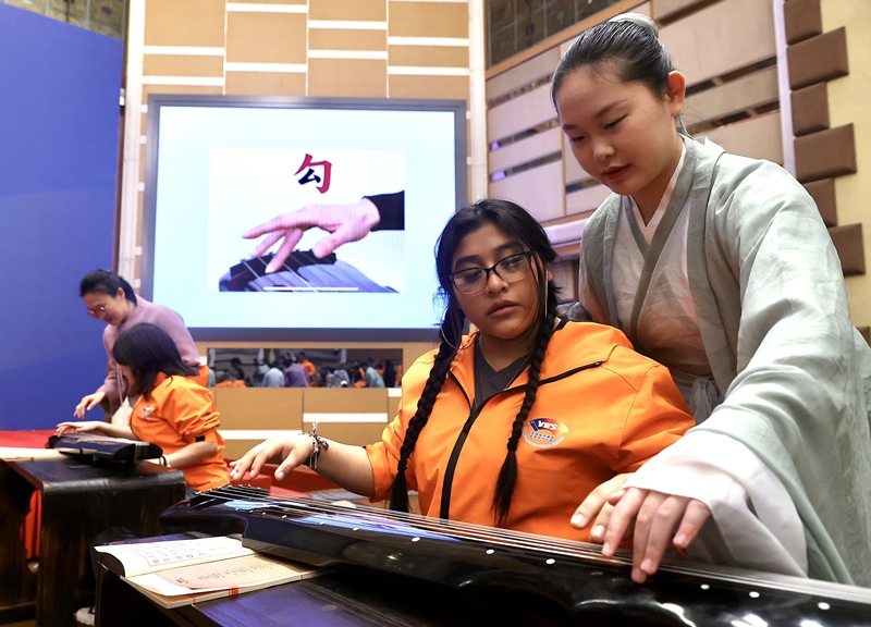 2024年3月20日，美國華盛頓州中學(xué)生代表團北京大學(xué)交流活動在北京大學(xué)英杰交流中心舉行。圖為來自華盛頓州的中學(xué)生體驗古琴。