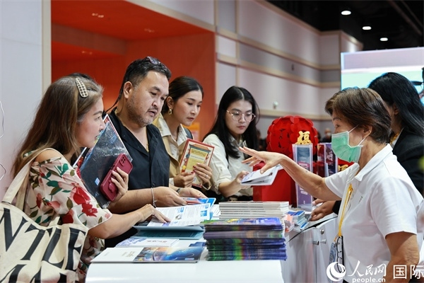 外國觀眾在中國展臺仔細閱讀赴華旅游介紹，向工作人員咨詢關于中國美食和景點的詳細信息。人民網(wǎng)記者 白元琪攝