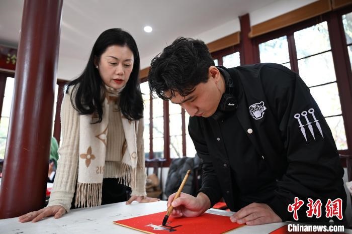 1月20日，外籍留學(xué)生在西泠印社社員李硯指導(dǎo)下寫福。當(dāng)日，來自巴西、馬來西亞、加納、哈薩克斯坦的外籍留學(xué)生在浙江杭州西泠印社體驗(yàn)福貼、春聯(lián)和篆刻，感受古老的中國(guó)傳統(tǒng)文化。中新社記者 王剛 攝