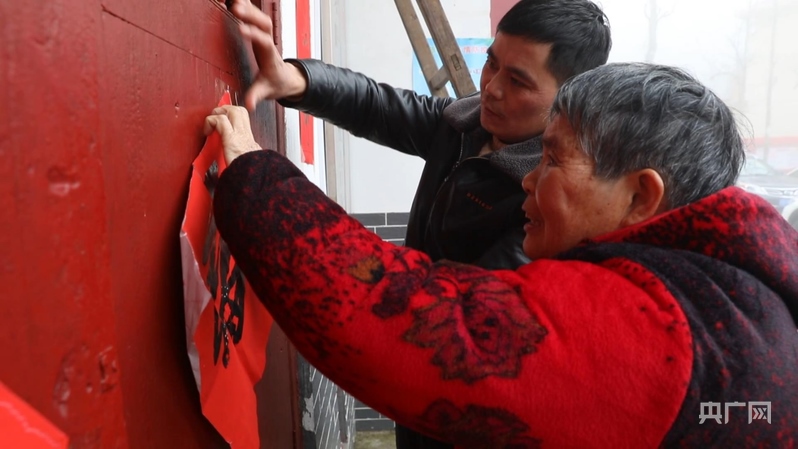 彭德良與70多歲母親貼春聯(lián)(央廣網(wǎng)記者 郇康新 攝)