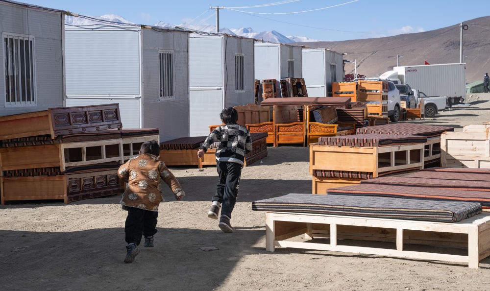 2025年1月13日，在定日縣嘎旦村，兩個孩子在剛運來的兩排藏床間奔跑。新華社記者丁增尼達 攝