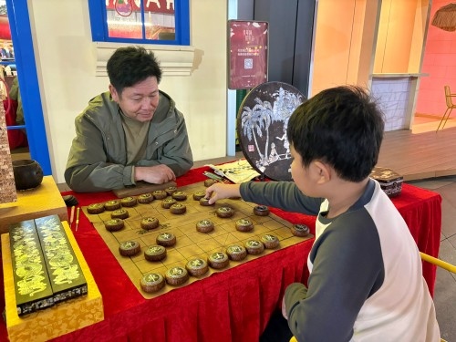 柯秋楓與市民下椰雕象棋。人民網(wǎng) 陳葉欣攝