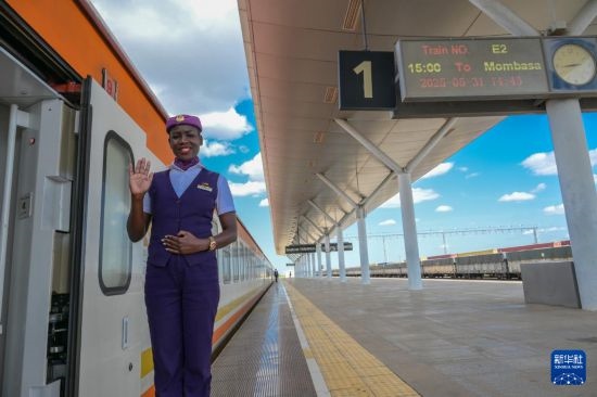 5月31日，在蒙內(nèi)鐵路內(nèi)羅畢站，一名乘務(wù)員在即將開往蒙巴薩的E2次列車旁等候乘客。新華社記者 楊光 攝