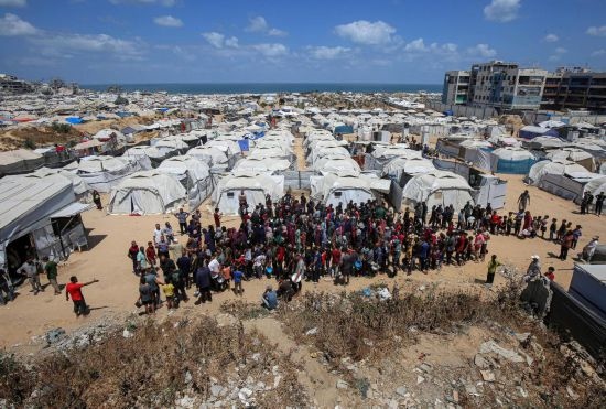 5月28日，人們?cè)诩由吵俏鞑康纳程犭y民營(yíng)等待領(lǐng)取救助食物。新華社發(fā)（里澤克·阿卜杜勒賈瓦德攝）